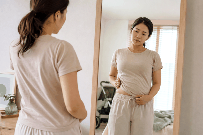 서초 산후다이어트 – 거울 앞에서 산후 체형을 살피는 여성